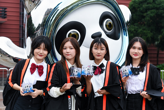 广州美术学院毕业生捧着冰墩墩在校园内拍照留念