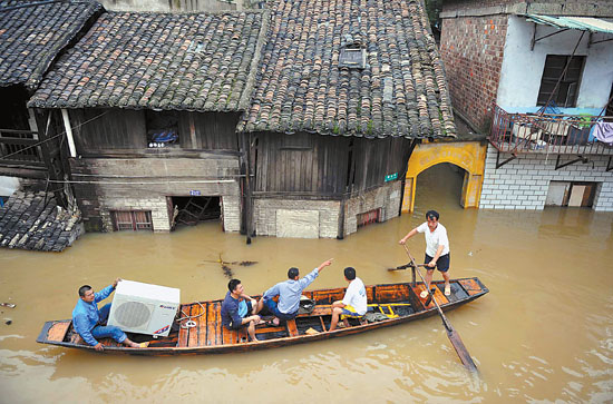 6月24日,湖南湘潭窑湾居民从被洪水吞没的家中转移物资
